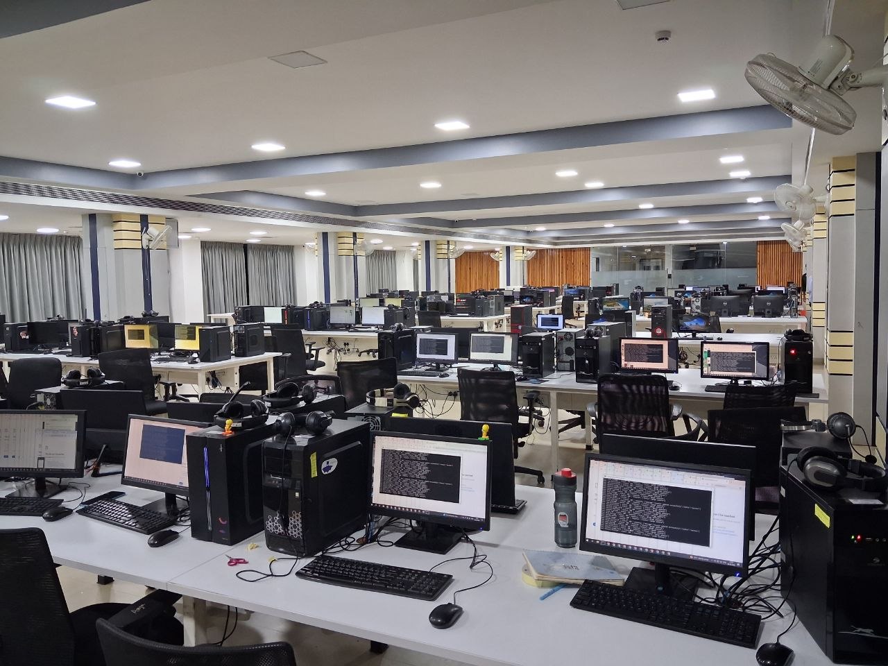 Desks with desktop computers and monitors in a large open office.