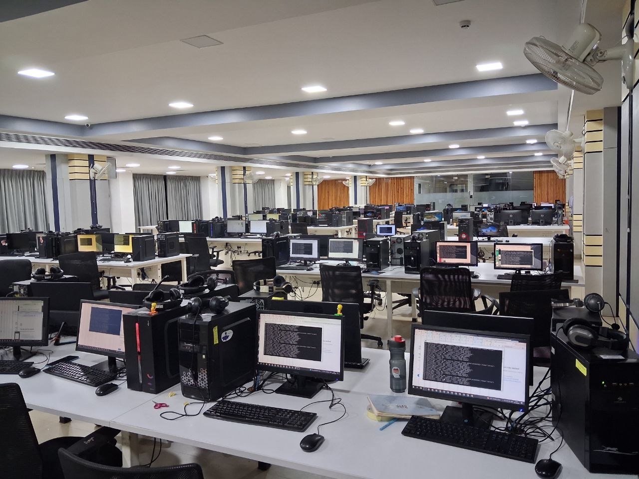 A wide view of an open-plan office with many workstations running.